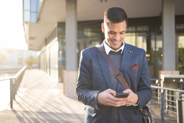 Hombre de negocios feliz o viaje con teléfono para redes sociales o comunicación en London street Busque correo electrónico o profesional en un teléfono inteligente 5g para investigar Internet o revisar blogs al aire libre