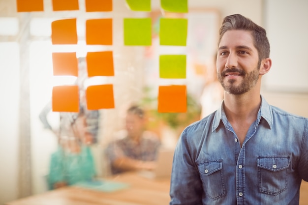 Hombre de negocios feliz que mira el poste está en la pared