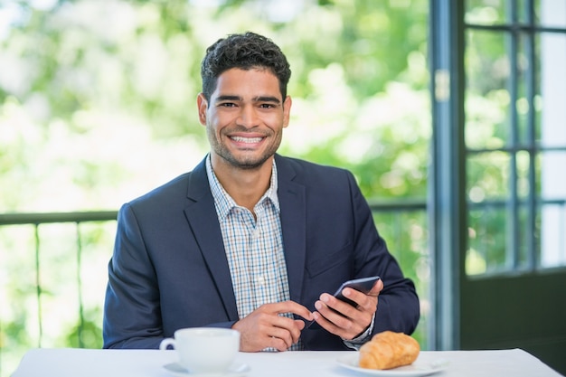 Hombre de negocios feliz que sostiene el teléfono móvil