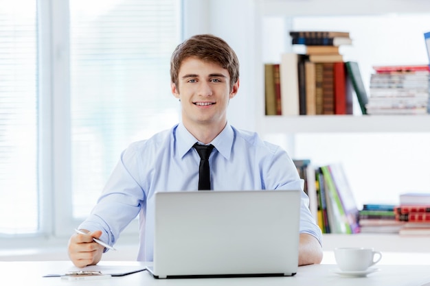 Hombre de negocios feliz que trabaja en la oficina en la computadora portátil