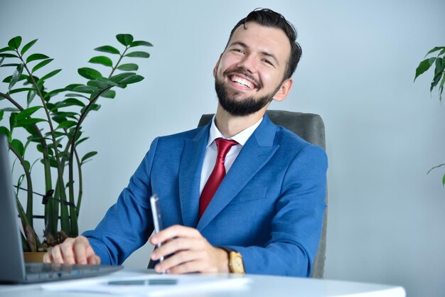 Hombre de negocios feliz sentado en la oficina moderna