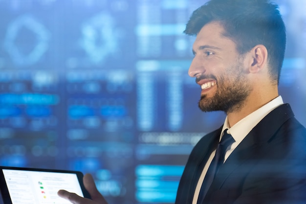 El hombre de negocios feliz sostiene una tableta en el fondo de la pantalla virtual