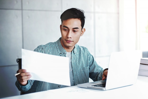 Hombre de negocios feliz trabajando en la computadora portátil y el documento en la oficina