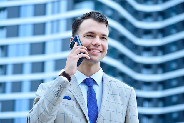 Un hombre de negocios feliz en traje hablando por teléfono móvil.