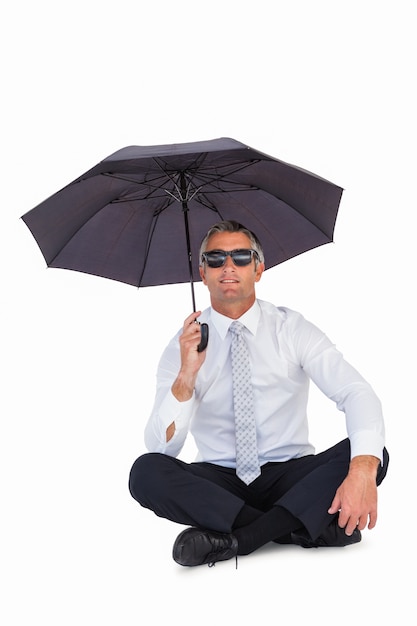 Hombre de negocios con gafas de sol y refugiarse con paraguas