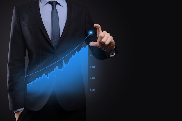 El hombre de negocios con gráficos holográficos y estadísticas del mercado de valores obtiene beneficios. Concepto de planificación del crecimiento y estrategia empresarial. Visualización de pantalla digital de buena forma económica.