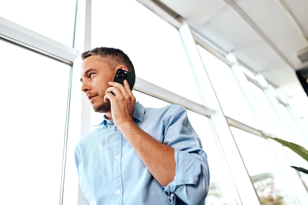 Hombre de negocios guapo hablando por teléfono en la oficina