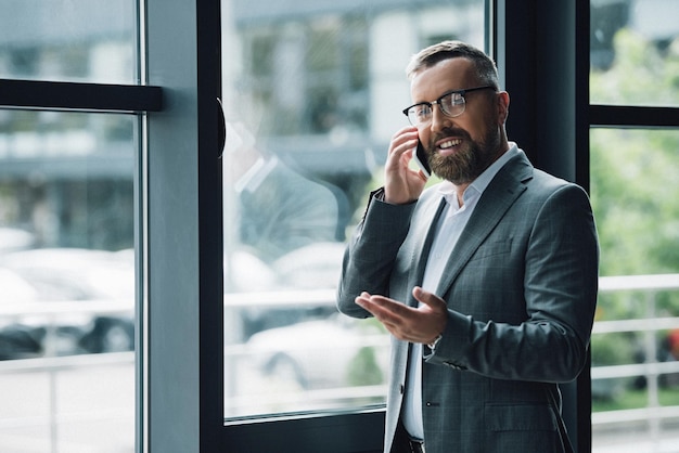 Hombre de negocios guapo con ropa formal y gafas hablando en su teléfono inteligente