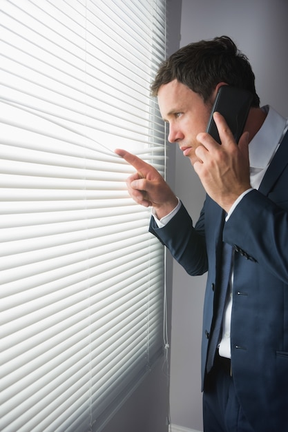 Hombre de negocios guapo serio mirando a través de la llamada telefónica ciega