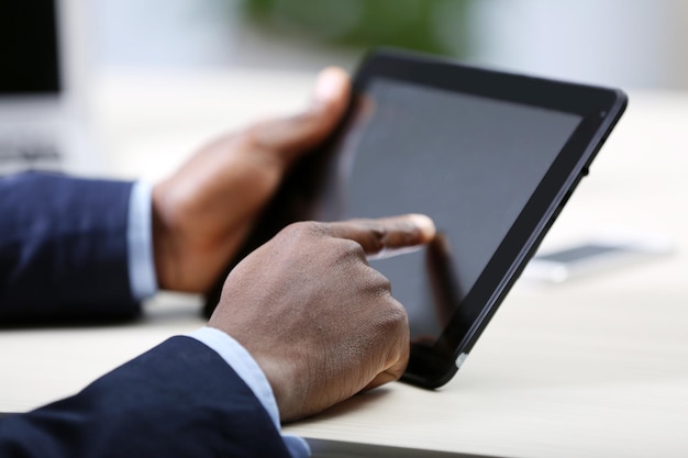 Hombre de negocios guapo con una tableta en su oficina vista trasera de cerca