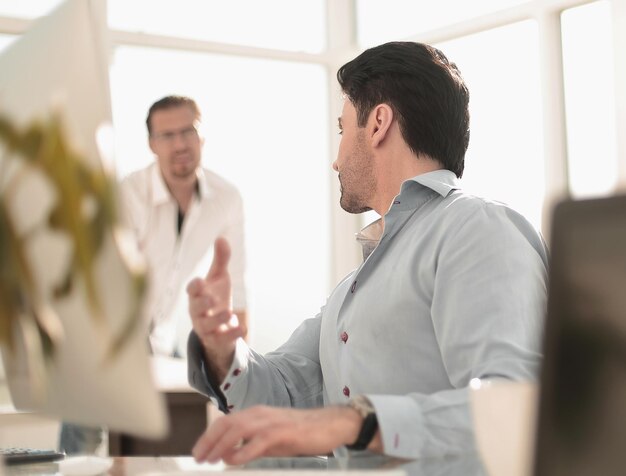 Hombre de negocios hablando con un colega sentado en su escritorio