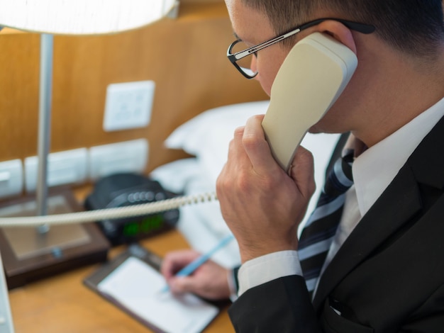 Hombre de negocios hablando por teléfono y usando notas de pluma