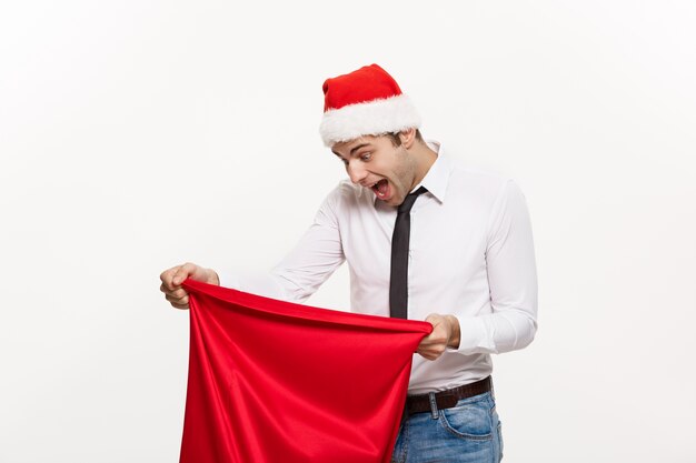 El hombre de negocios hermoso celebra Feliz Navidad y la Feliz Año Nuevo usan el sombrero de santa con el bolso grande rojo de Santa.