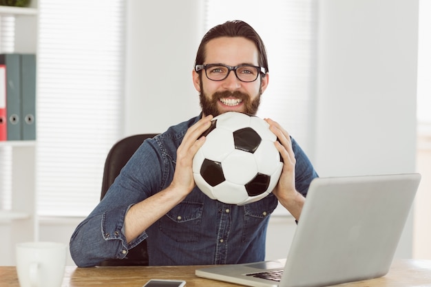 Hombre de negocios hipster sosteniendo un balón de fútbol