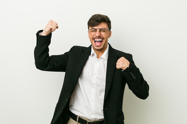 Hombre de negocios hispano joven levantando el puño después de una victoria, ganador.