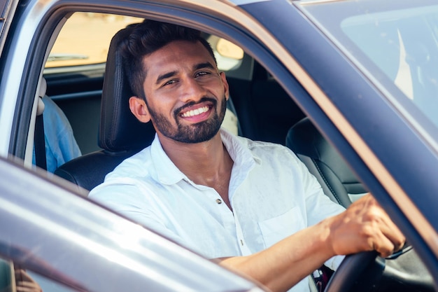 Hombre de negocios indio parado cerca del auto al aire libre en la playa del mar verano buen día. un hombre con una camisa blanca y una sonrisa blanca como la nieve regocijándose comprando un auto nuevo disfrutando de unas vacaciones junto al océano