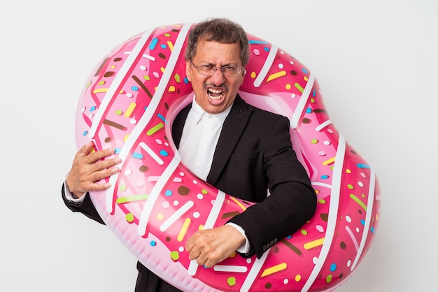 Hombre de negocios indio Senior sosteniendo donut inflable aislado sobre fondo blanco gritando muy enojado y agresivo.