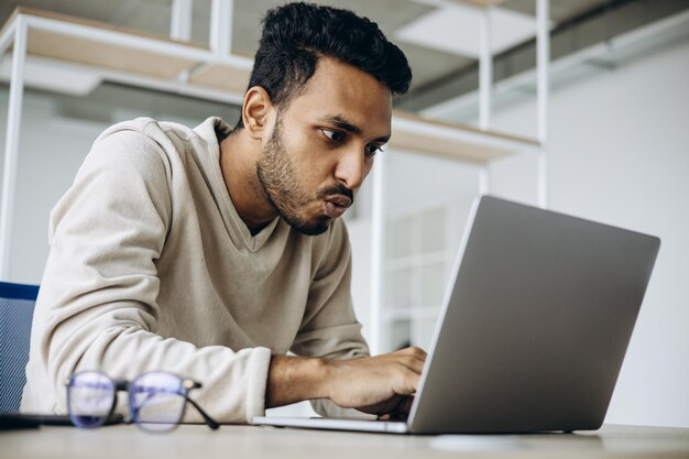 Hombre de negocios indio sentado en la oficina trabajando en una computadora portátil