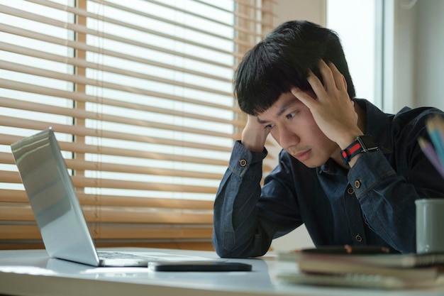 Hombre de negocios infeliz que cubre la cara con la mano sintiendo estrés dolor de cabeza migraña que tiene problemas con el proyecto