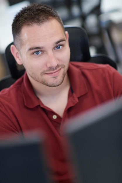 hombre de negocios informal que trabaja en una computadora de escritorio en el moderno interior de la oficina de inicio de planta abierta