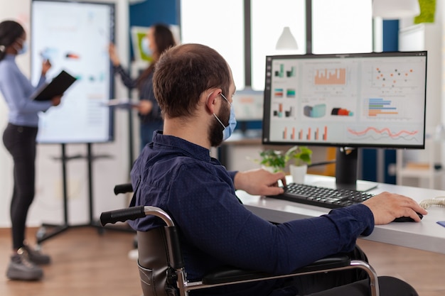 Hombre de negocios inmovilizado con máscara protectora que trabaja en una nueva empresa normal ...