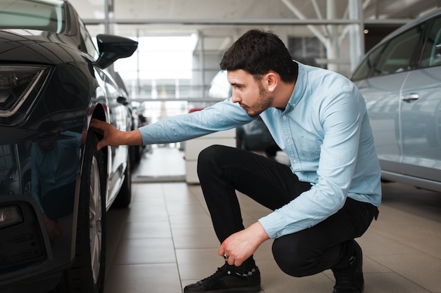 Hombre de negocios inspecciona un auto nuevo en concesionario