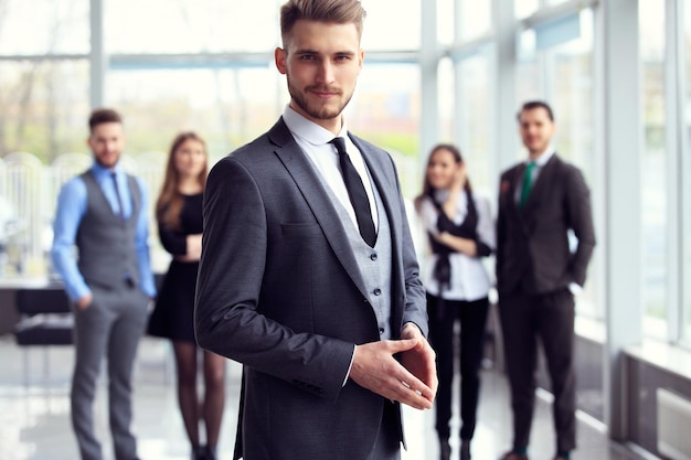 Hombre de negocios inteligente feliz con compañeros de equipo discutiendo en el fondo