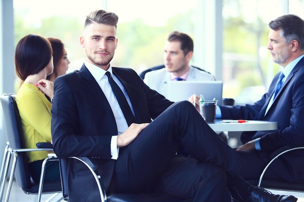 Hombre de negocios inteligente feliz con compañeros de equipo discutiendo en el fondo