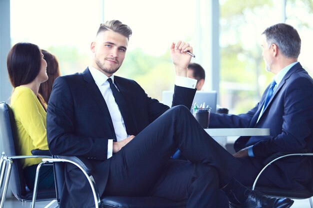 Foto hombre de negocios inteligente feliz con compañeros de equipo discutiendo en el fondo