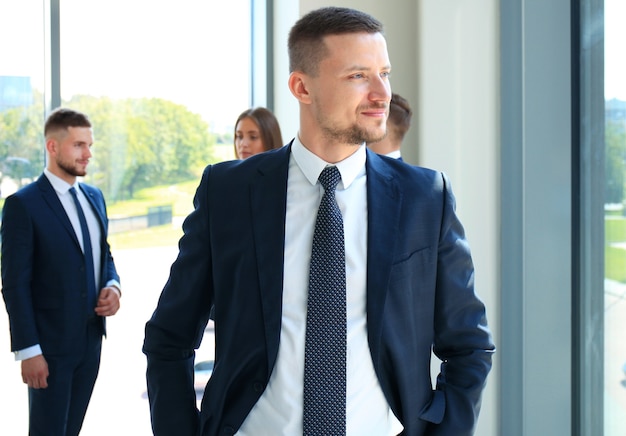 Hombre de negocios inteligente feliz con compañeros de equipo discutiendo en el fondo