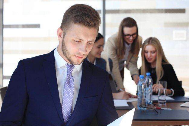 Hombre de negocios inteligente feliz con compañeros de equipo discutiendo en el fondo