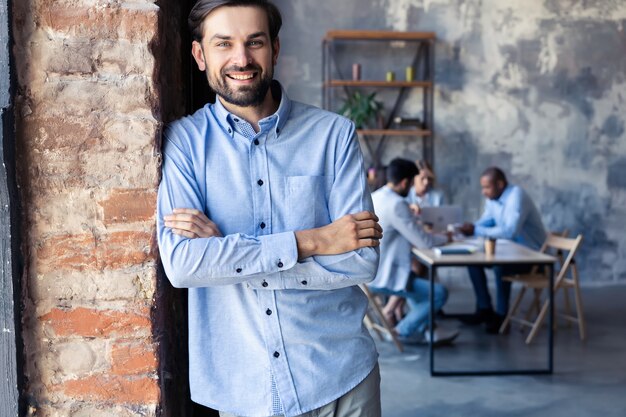 Foto hombre de negocios inteligente feliz con compañeros de equipo discutiendo en segundo plano.