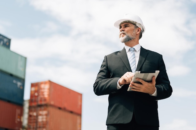 Foto hombre de negocios inteligente en traje negro con tableta comprobando mercancías en la estación de carga