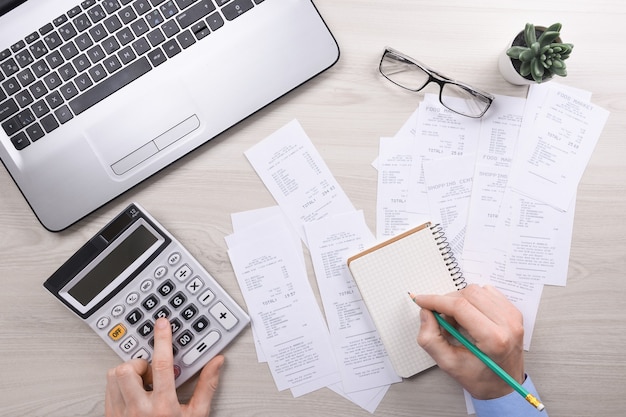 Foto hombre de negocios irreconocible que usa la calculadora en la oficina de escritorio y escribe anotaciones con calcular el costo en la oficina en casa