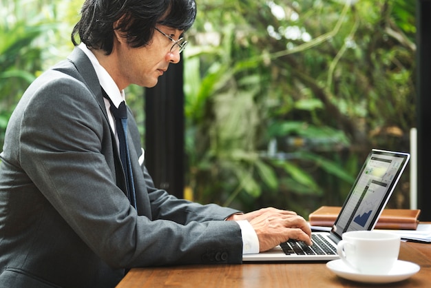 Hombre de negocios japonés que trabaja en la computadora portátil