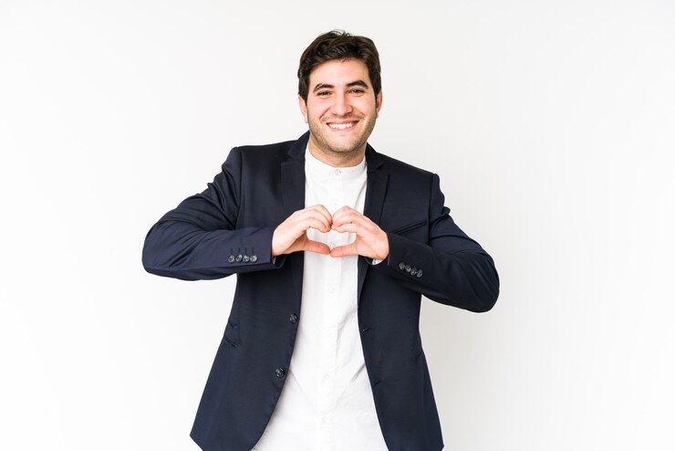 Foto hombre de negocios joven aislado en blanco sonriendo y mostrando una forma de corazón con las manos.