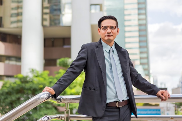 Hombre de negocios joven de Asia delante del edificio moderno en el centro de la ciudad. Concepto de hombres de negocios jovenes