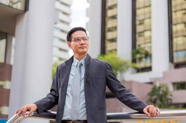 Foto hombre de negocios joven de asia frente al moderno edificio en el centro de la ciudad