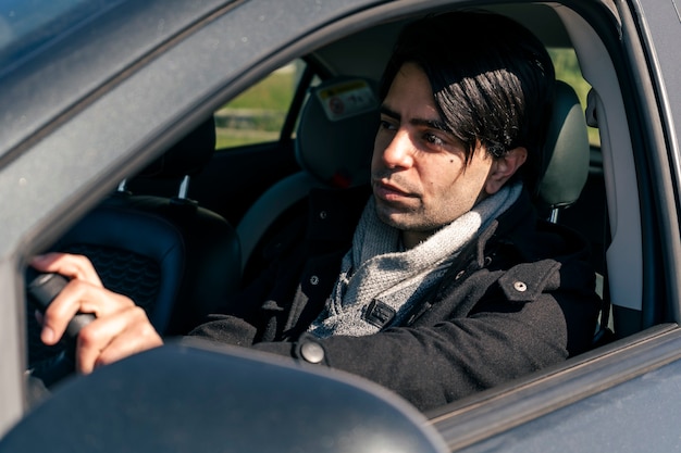 Hombre de negocios joven atractivo que conduce un coche. Concepto de transporte y comunicaciones terrestres.