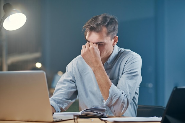 Hombre de negocios joven cansado que toma notas en su cuaderno