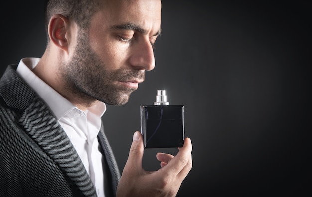 Foto hombre de negocios joven caucásico que huele el perfume.