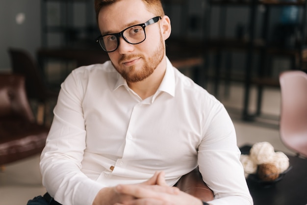 Hombre de negocios joven creativo con gafas elegantes en ropa de moda mirando a otro lado