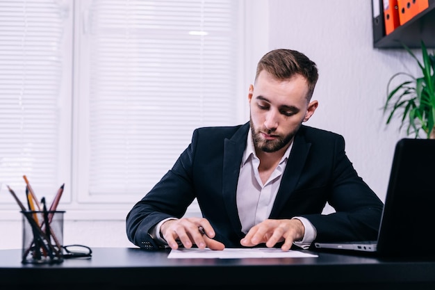 Hombre de negocios joven escribiendo notas en un papel Sitt ejecutivo masculino
