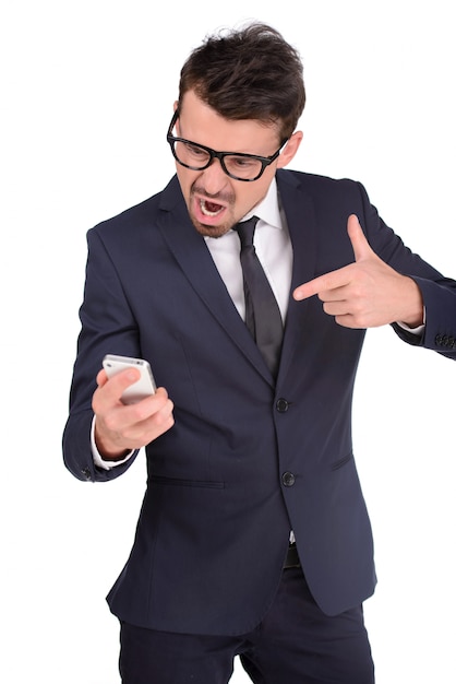 Hombre de negocios joven furioso que sostiene un teléfono móvil.