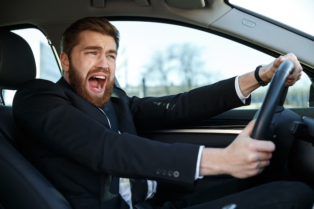 Hombre de negocios joven gritando entrar en accidente automovilístico mientras conduce