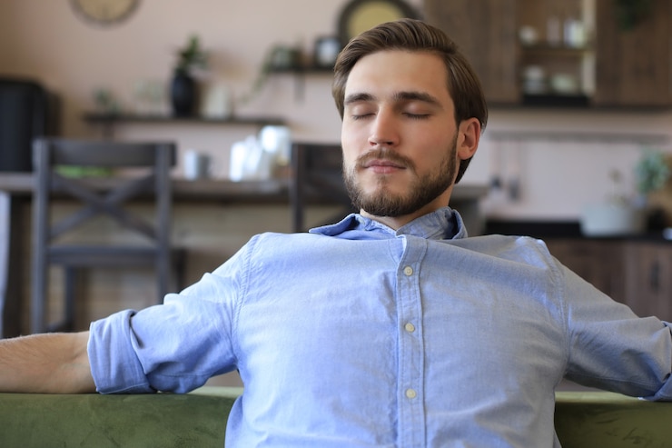 Foto hombre de negocios joven guapo parece relajado mientras está sentado en el sofá en casa.