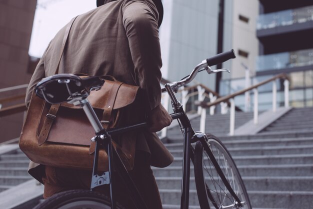 Hombre de negocios joven guapo con su bicicleta moderna.