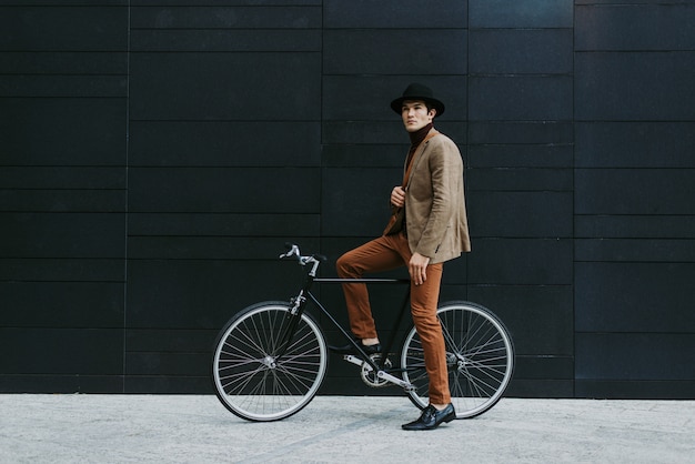 Hombre de negocios joven guapo con su bicicleta moderna.