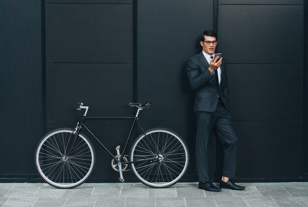 Hombre de negocios joven guapo con su bicicleta moderna.