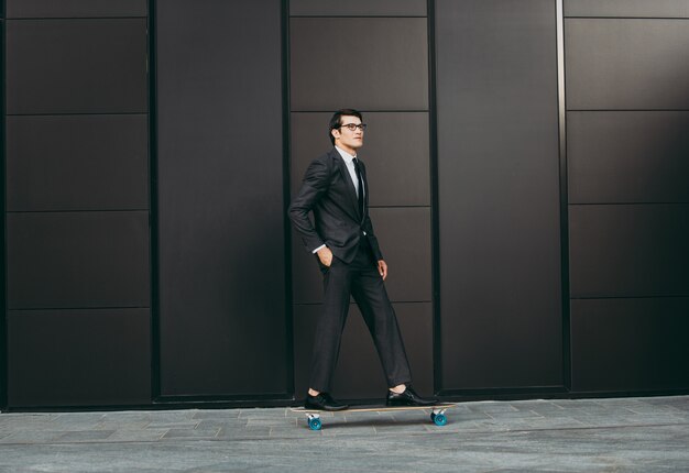 Hombre de negocios joven guapo con su longboard moderno